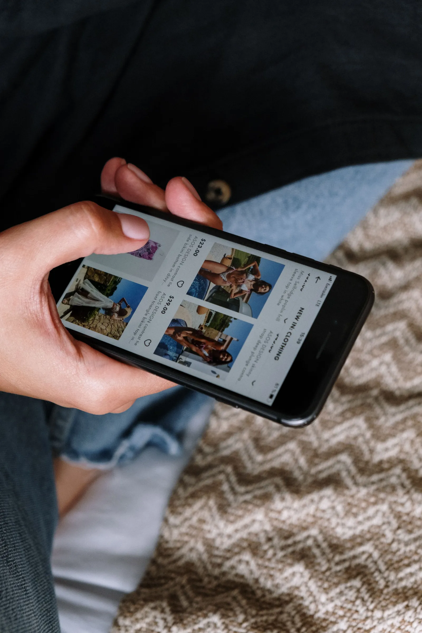 A hand holding a smartphone with a shopping app open
