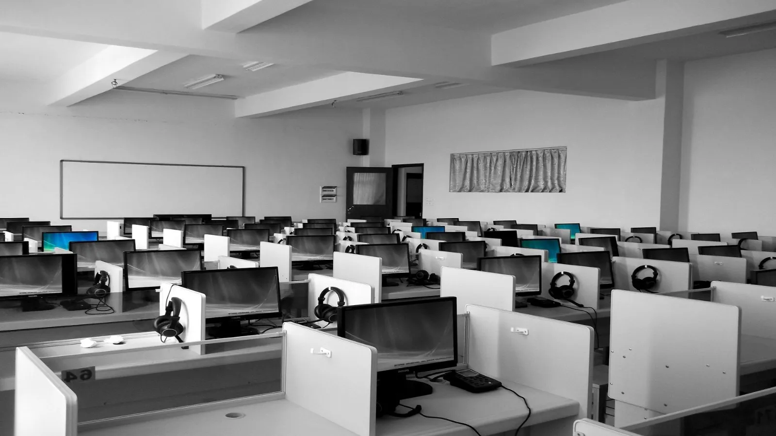 Rows of empty call centre desks with monitors and headsets